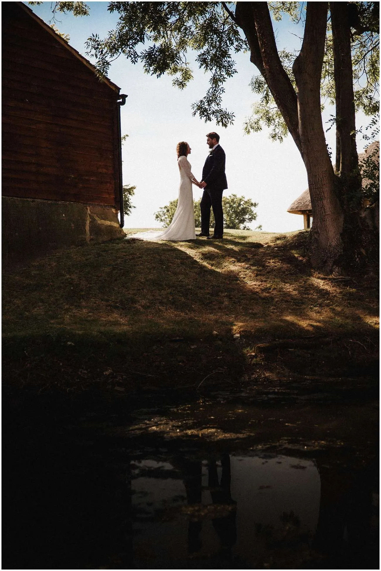 Bride and groom hold hands by the lake at Colville Hall