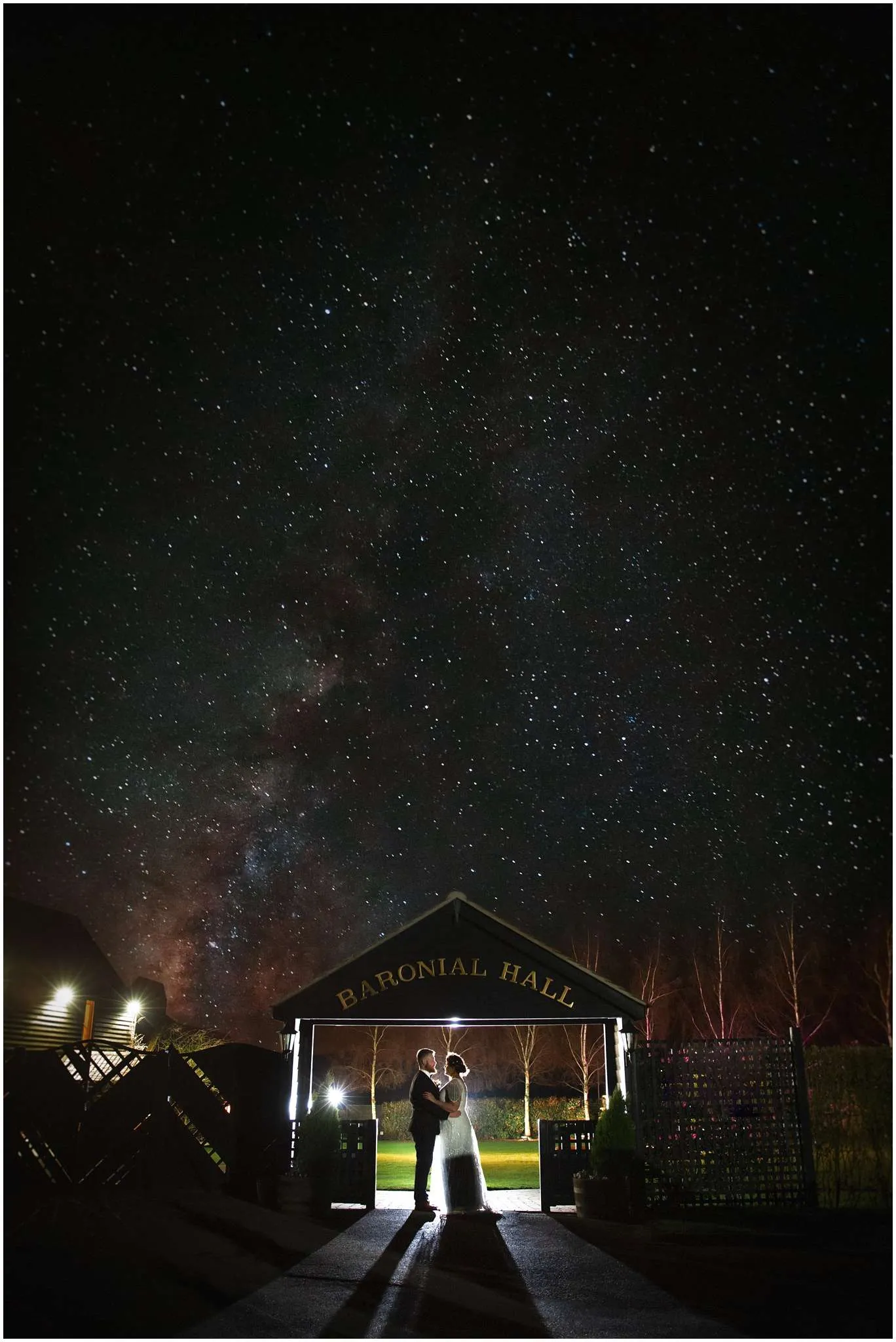 The bride and groom hold each other under a sign at Crondon Park with the stars in the sky.
