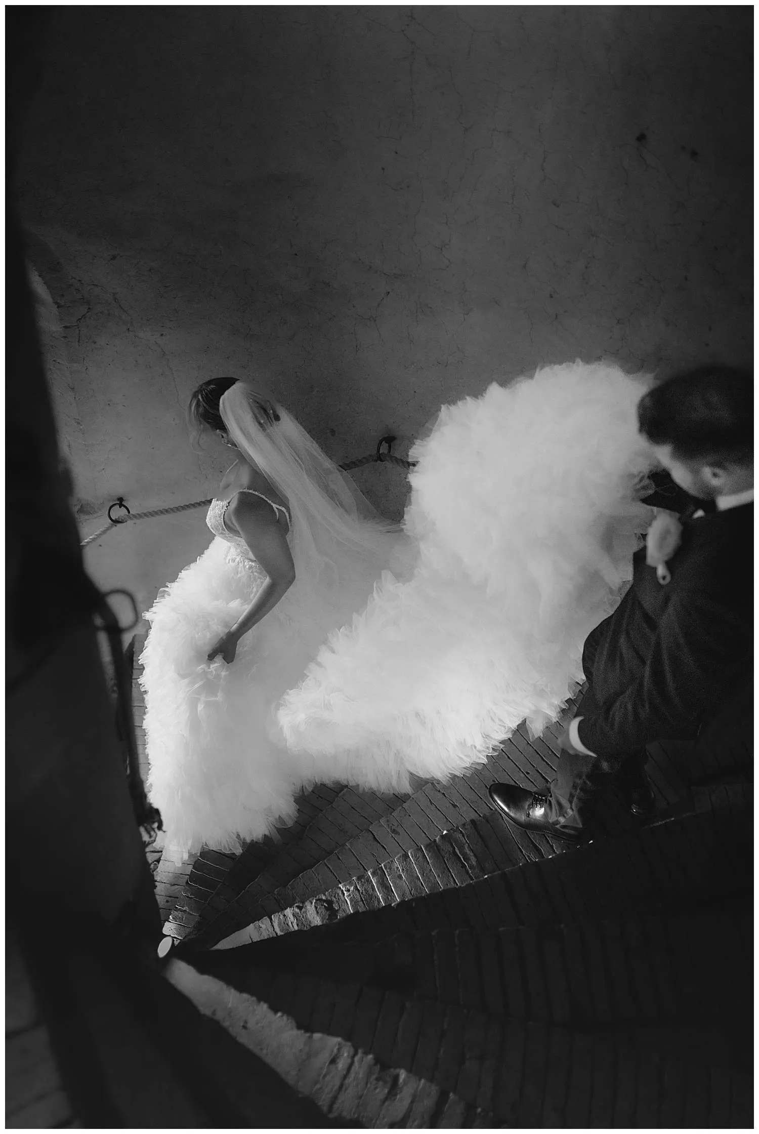 Hedingham Castle Wedding Photographer - the bride walks down the castle stairs in her dress