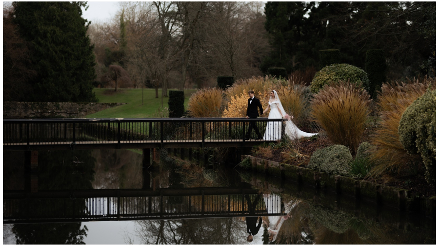 Wedding at the Orangery - The couple walk across a picturesque bridge