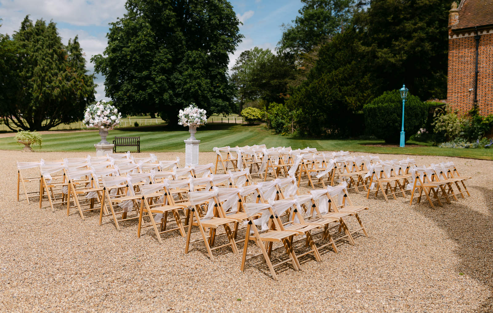 Outdoor courtyard wedding ceremony setup at Gosfield Hall with white floral arrangements