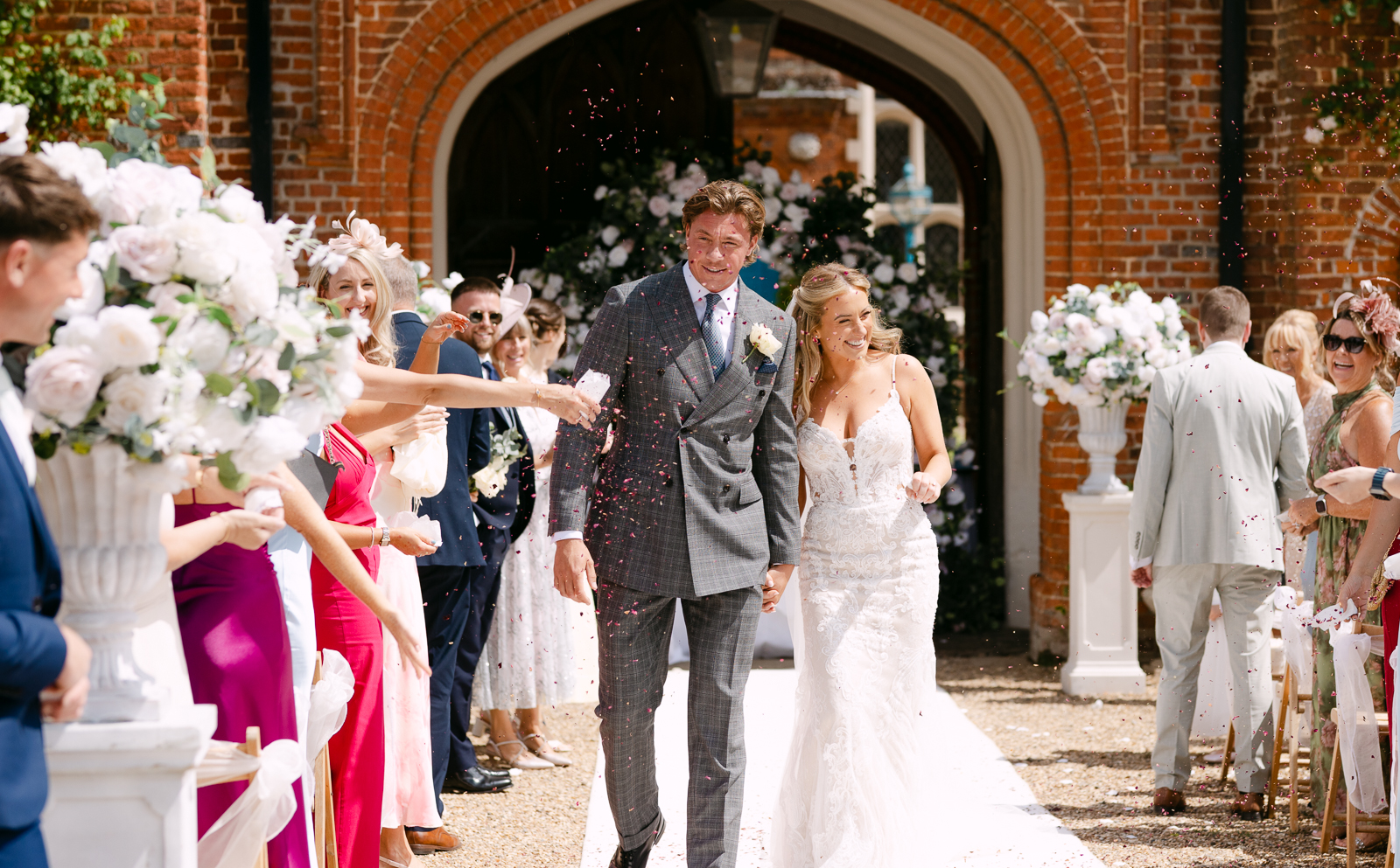 Molly and Taylor walking through confetti after their Gosfield Hall wedding ceremony